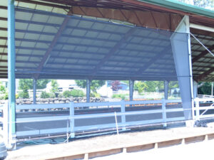 A GaleShield CABLE MOUNT Screen Kit installed on an arena Side wall for protection from wind, rain, snow, sleet and hot, drying sun.